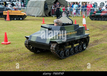 Un bambino piccolo la guida un modello di serbatoio militare intorno a un campo in Eastbourne Air Show Foto Stock