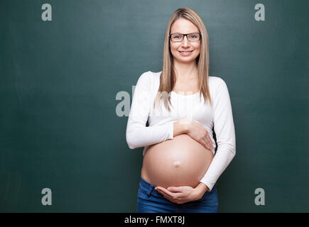 Giovane donna in stato di gravidanza e di una lavagna con copyspace Foto Stock