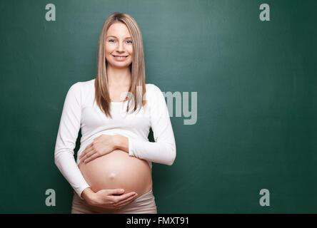 Giovane donna in stato di gravidanza e di una lavagna con copyspace Foto Stock