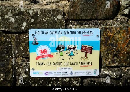 Bilingue grazie per mantenere la nostra spiaggia libera di fumo segno su una parete al di sopra di Little Haven Beach Pembrokeshire Coast National Park Foto Stock