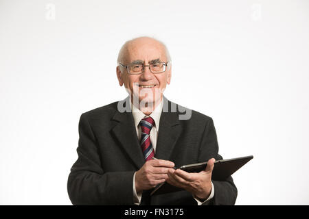Vecchio imprenditore senior lavora con nero computer tablet, indossa una tuta di business Foto Stock