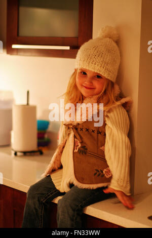 Felice anno tre vecchi, ragazza bionda bambino kid, indossando una crema bobble pom pom hat e gilet di pelliccia, dolce concetto innocenti, infanzia innocenza Foto Stock