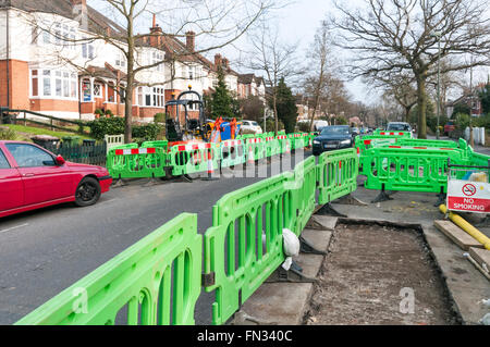 Il traffico che passa anche se lavori su un suburban strada residenziale. Causato dalla sostituzione della rete del gas. Foto Stock