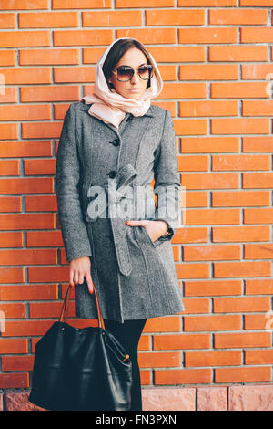 Ragazza in posa su uno sfondo di rosso la parete in mattoni Foto Stock