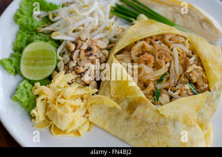 Il cibo thai Pad Thai , STIR FRY tagliatelle con carne di maiale.avvolgere le uova sulla piastra bianca decorata con condimenti vari. Foto Stock