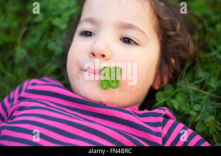 Felice bambina di tre anni a suonare in erba prato con trifogli. Messa a fuoco selettiva Foto Stock