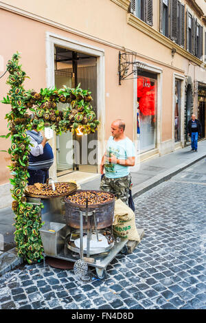 Uomo locale, un venditore ambulante che vende castagne arrostite sulla banchina di una strada a ciottoli, Scalinata di piazza di Spagna, Roma, Italia Foto Stock