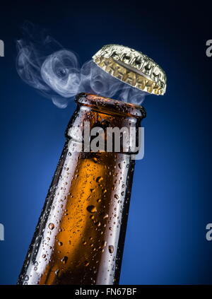 Apertura del tappo di birra con il gas in uscita. Foto Stock