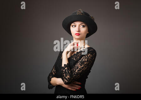 In disperato bisogno. Close up di poveri triste premuto giovane donna a mendicare per aiutare e andando a piangere mentre isolare permanente su nero Foto Stock