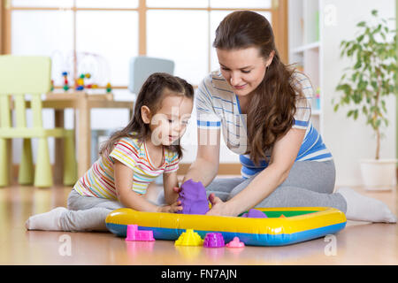 La ragazza del bambino e la madre gioca con la costruzione di sabbia giocattolo a casa Foto Stock