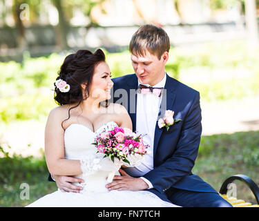 Matrimonio sposa e lo sposo su un banco di lavoro con la natura paesaggio paesaggio sullo sfondo Foto Stock