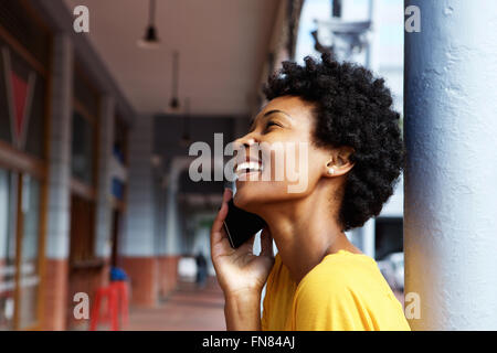 Closeup ritratto di un sorridente giovane donna africana parlando al telefono cellulare all'aperto Foto Stock