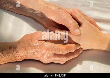 Le mani di Nonna e nipote nel letto Foto Stock