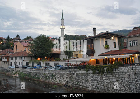 Un minareto sorge su edifici attraverso il fiume dalla città vecchia di Sarajevo, Bosnia Erzegovina. Foto Stock