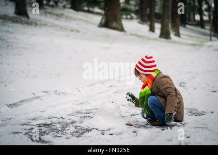 Ragazzo costruire un pupazzo di neve Foto Stock