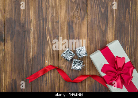 Regalo bianco seta rossa avvolgere con decorazione su sfondo di legno Foto Stock