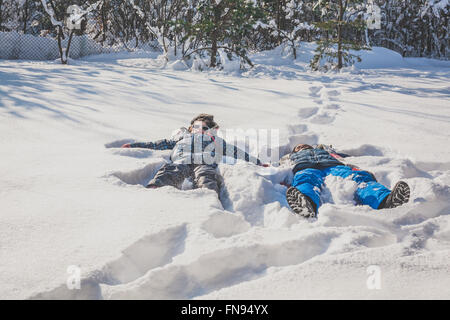 Un ragazzo e una ragazza che giace in snow making angeli di neve nella neve Foto Stock