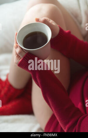 Close-up di una donna seduta su un divano con una tazza di tè Foto Stock