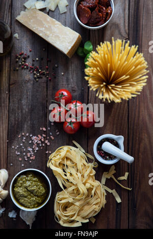 La pasta, pesto, aglio, pomodori e parmigiano sul tavolo Foto Stock