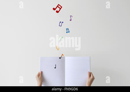 Donna che mantiene un notebook con note musicali volare pagina Foto Stock