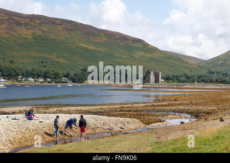 Una famiglia sul bordo del mare loch a Lochranza, Isle of Arran, con i resti del suo piccolo castello.