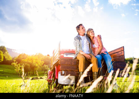 Coppia senior seduti nel retro del rosso carrello elevatore di prelievo Foto Stock