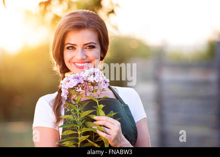 Giovani giardiniere nel suo giardino di fiori di contenimento, carattere solare Foto Stock