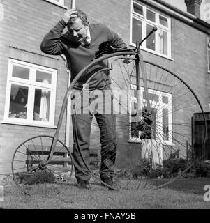 Uomo con Penny Farthing bicicletta in bisogno di riparazione con una ruota deformata 1960s Foto Stock