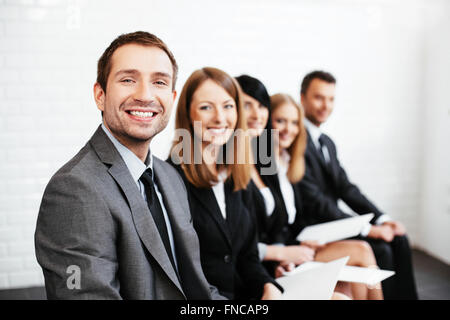 Fiducioso imprenditore seduto con i partner aziendali in background Foto Stock