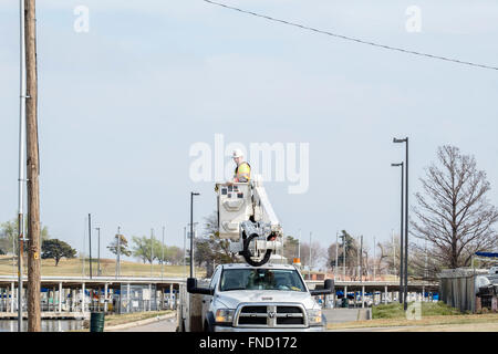 Un lineman viene abbassata al suolo in un sollevamento benna dopo la riparazione di una linea elettrica. Oklahoma City, OK, Stati Uniti d'America. Foto Stock