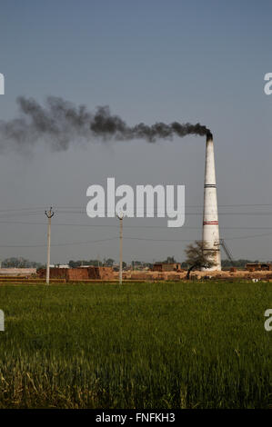 Un clan di mattoni di emissione di fumo nero dal suo camino nella periferia di Nuova Delhi, India Foto Stock