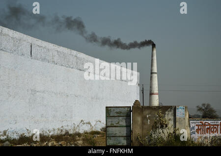 Un clan di mattoni di emissione di fumo nero dal suo camino nella periferia di Nuova Delhi, India Foto Stock