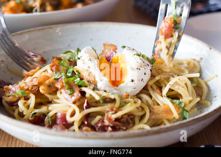 Uovo affogato su spaghetti con pancetta e l'aglio Foto Stock