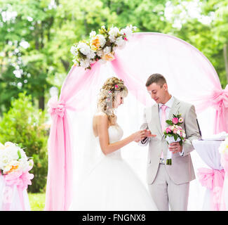 Sposa di mettere un anello sul govern dito durante la cerimonia nuziale Foto Stock