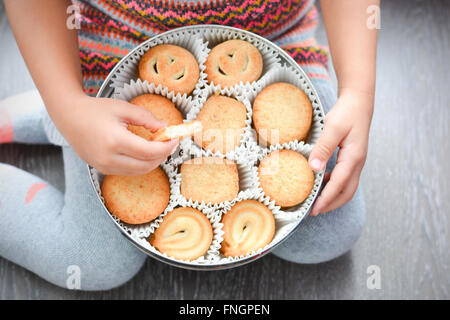 Bambino in possesso di una scatola di burro danese i cookie Foto Stock