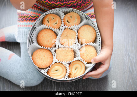 Bambino in possesso di una scatola di burro danese i cookie Foto Stock