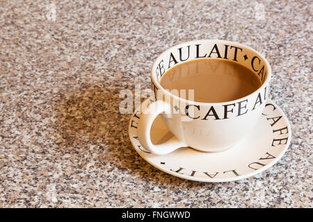 Una rotonda grande tazza di caffè bianco su un piattino di adattamento su un piano di lavoro in marmo granito Foto Stock