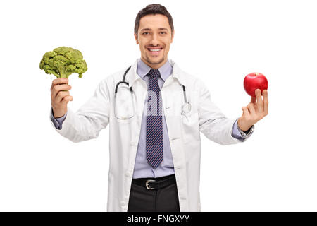 Giovani allegro nutrizionista tenendo un pezzo di broccoli e un apple isolati su sfondo bianco Foto Stock