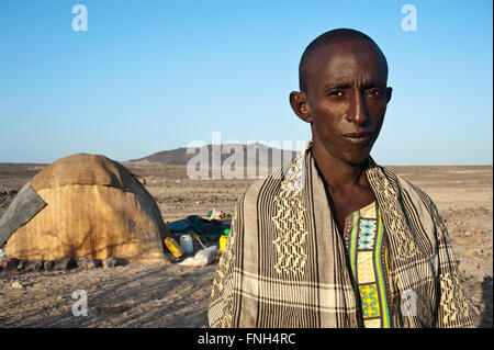L'uomo appartenente all'etnia afar. Sullo sfondo la capanna dove la sua famiglia vive in Etiopia () Foto Stock