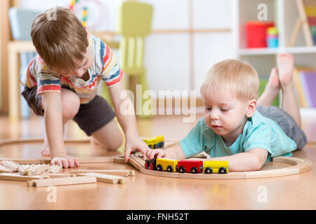 Carino bambini che giocano con treni di legno. Il Toddler bambini a giocare con i blocchi e i treni. Ragazzi giocattolo costruzione ferrovia a casa o asilo nido. Foto Stock