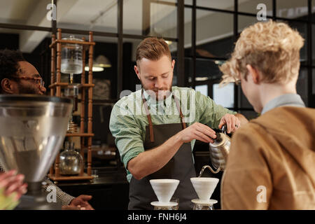 Barista versando il caffè fresco attraverso il filtro in moderno cafe Foto Stock