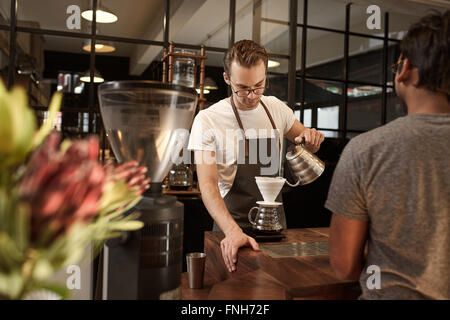 Barista versando il caffè attraverso il filtro in moderno cafe Foto Stock