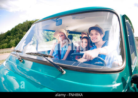 Hipster boy il pilotaggio di un vecchio camper con adolescenti, roadtrip Foto Stock