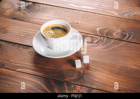 Una bella tazza di caffè con due zollette di zucchero i cubi su vecchio sfondo di legno Foto Stock