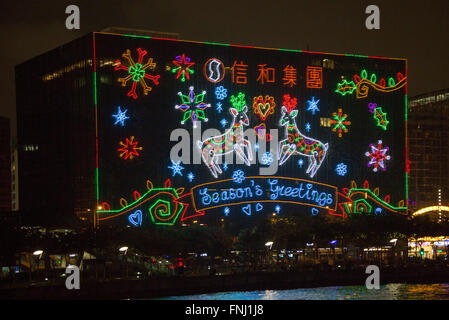 Tanti auguri Giant natalizi display luci di notte su edifici del porto di Victoria Isola di Hong Kong Foto Stock