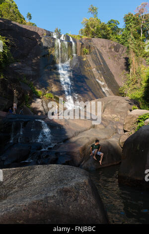 Uomo seduto sulle rocce in pozzetti di sette cascate, Langkawi, Malesia Foto Stock
