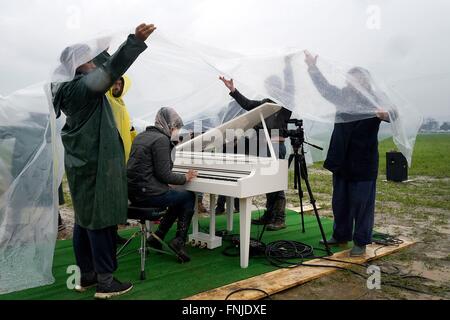 Idomeni, Grecia. Xii marzo, 2016. migliaia di migranti sono bloccati con la chiusura del confine tra la Grecia e la Macedonia 10.000 persone sono ora sul confine,in condizioni disperate.Nella foto un rifugiato suona il pianoforte sotto la pioggia Photo credit: Danilo Balducci/Sintesi/Alamy Live News Foto Stock