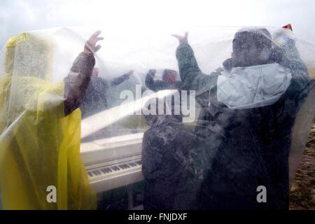 Idomeni, Grecia. Xii marzo, 2016. migliaia di migranti sono bloccati con la chiusura del confine tra la Grecia e la Macedonia 10.000 persone sono ora sul confine,in condizioni disperate.Nella foto un rifugiato suona il pianoforte sotto la pioggia Photo credit: Danilo Balducci/Sintesi/Alamy Live News Foto Stock