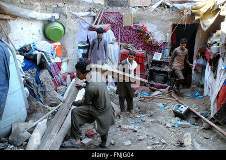 La gente guarda roba danneggiato che era stato distrutto quando il tetto della loro casa era crollato durante pioggia pesante dopo il crollo del tetto incidente nella zona Saeedabad nella città di Peshawar Martedì, Marzo 15, 2016. Foto Stock