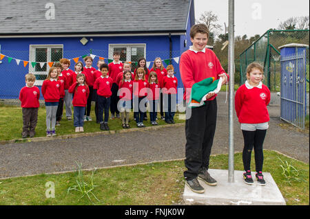 Durrus, Irlanda. Il 15 marzo, 2016. Gli alunni Stephen Dukelow e Anna Walker prepara ad alzare il tricolore irlandese mentre gli altri alunni guardare al St James Scuola nazionale, Durrus, sulla proclamazione giorno che era stata organizzata per commemorare gli eventi del 1916. Credito: Andy Gibson/Alamy Live News. Foto Stock